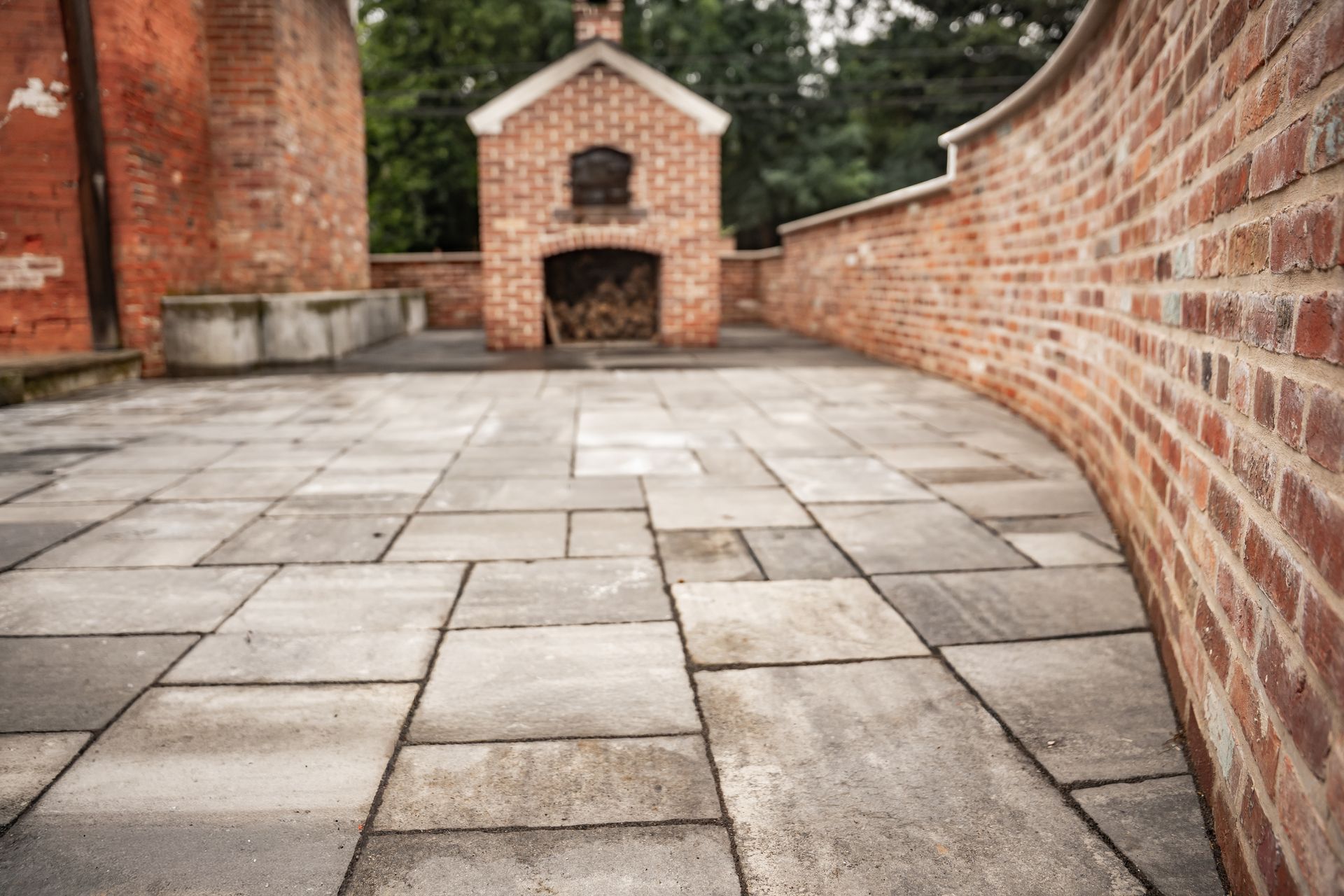 Stone-paved courtyard beside red brick walls and a small brick oven or fireplace