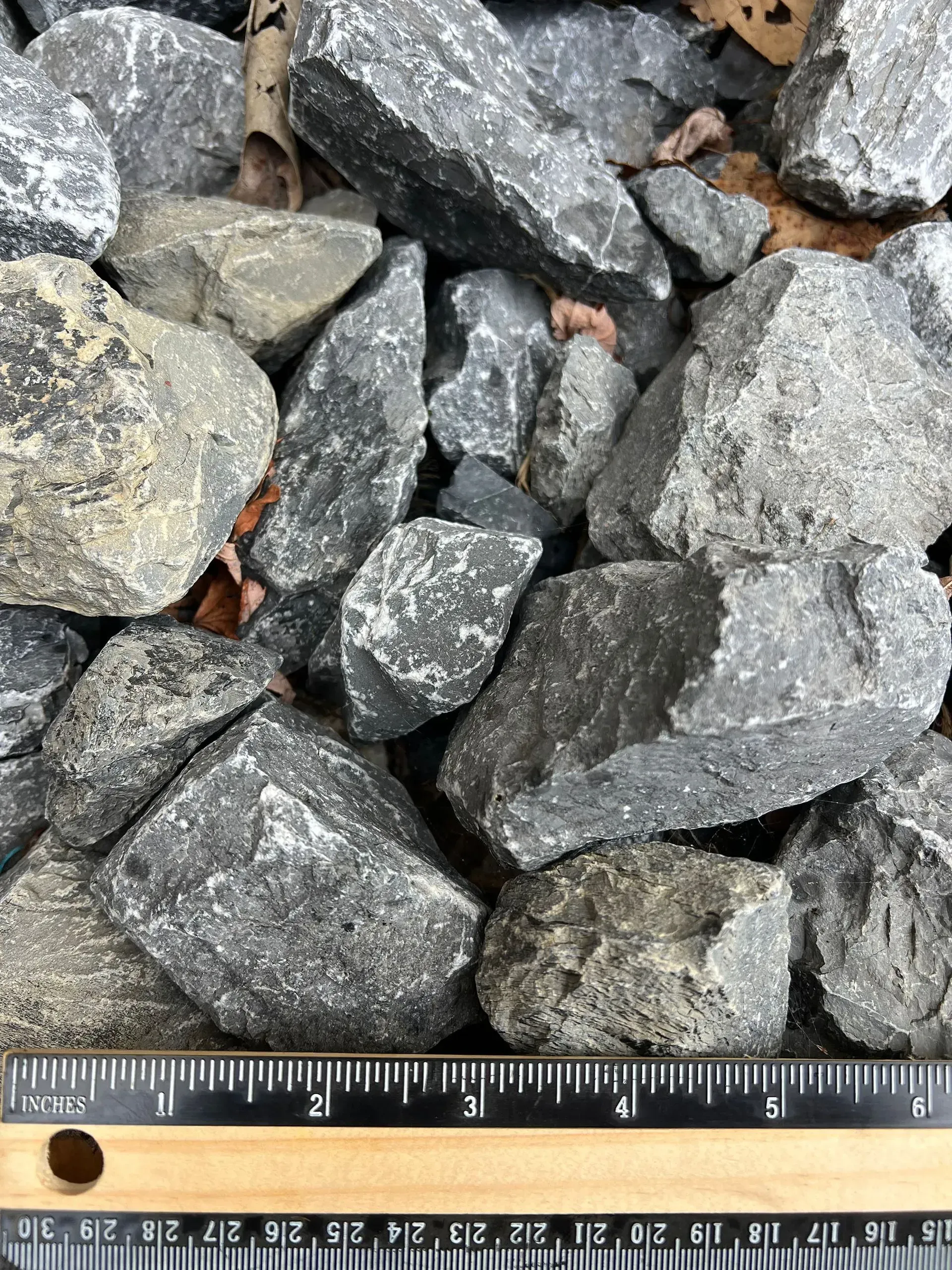 Pile of gray gravel stones with a ruler at the bottom for scale