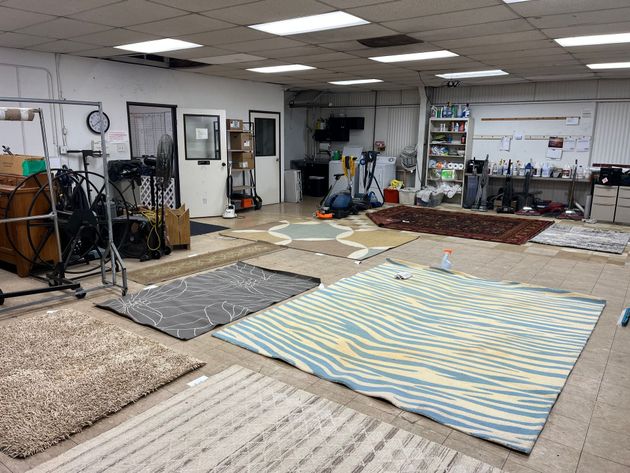 Indoor room with several rugs or mats laid out on the floor and exercise equipment in the background.