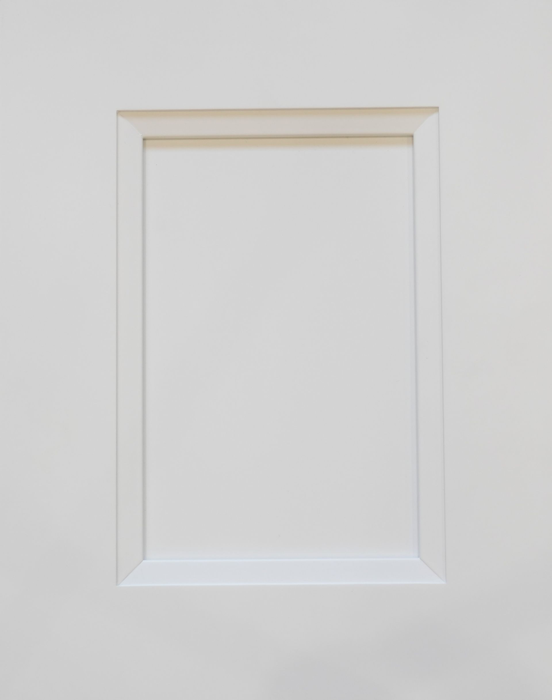 White recessed wall panel with a simple decorative frame on a light gray wall
