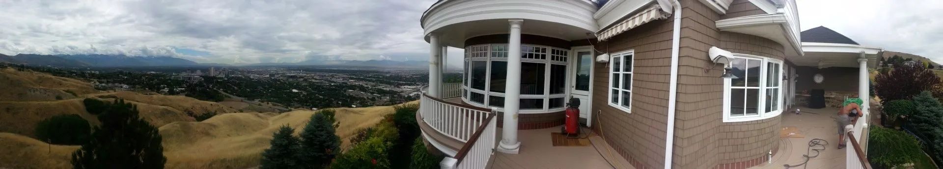 Panoramic view from a house porch overlooking a green valley and cloudy sky