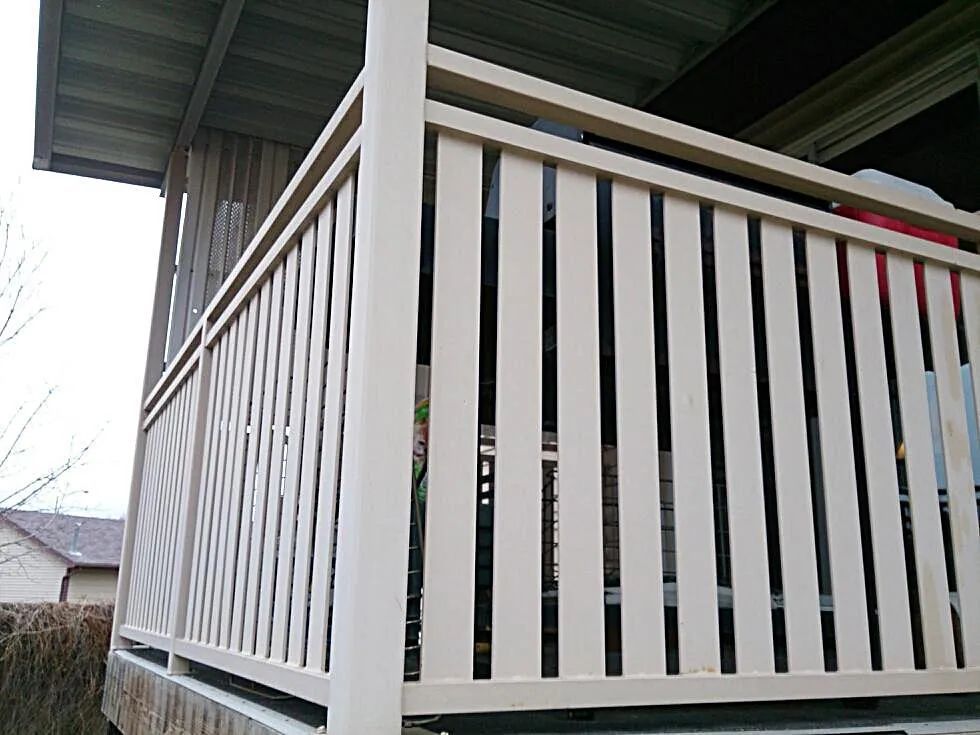 White wooden porch railing under a green roof, viewed from the corner.