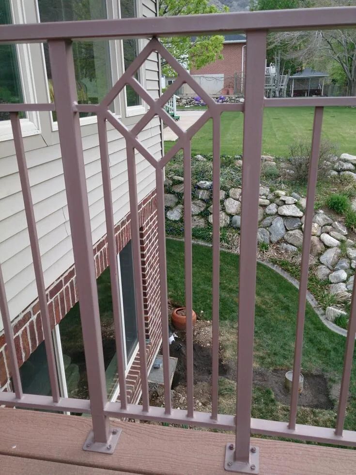 Pink-painted deck railing overlooking a yard with rocks, grass, and a house exterior