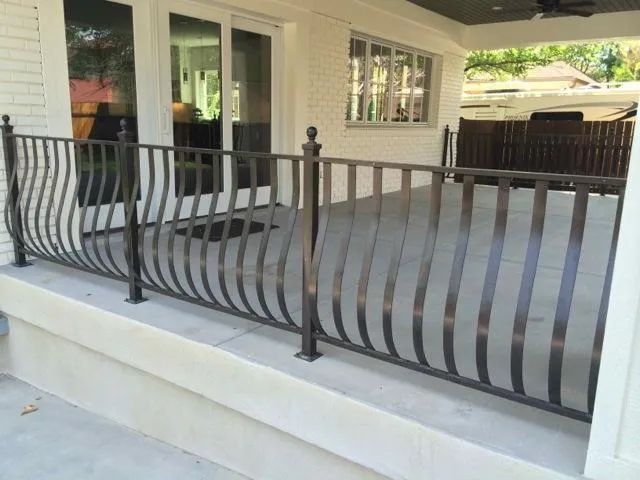 Front porch with black wrought-iron railing and light gray steps outside a house