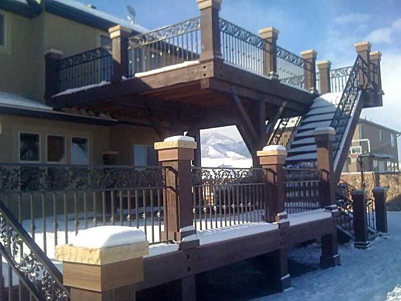 Snow-covered wooden deck with railings and stairs outside a building