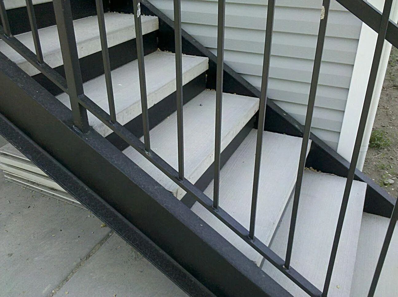 White outdoor staircase with gray metal railings and concrete steps on a porch