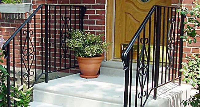 Brick front steps with black railings and a potted plant at the entrance