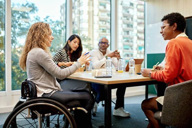 A woman in a wheelchair is sitting at a table with other people.