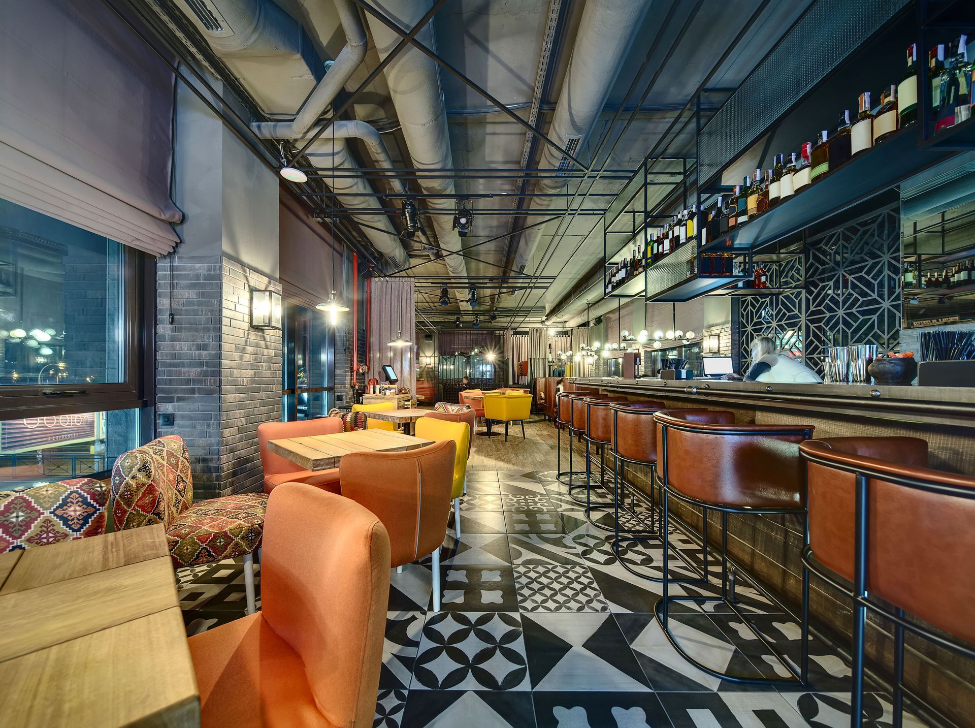 A restaurant with tables and chairs and a long bar.