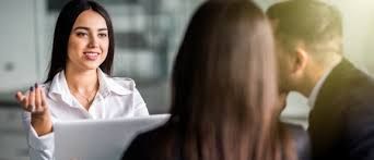 A woman is sitting at a table talking to a man and a woman.