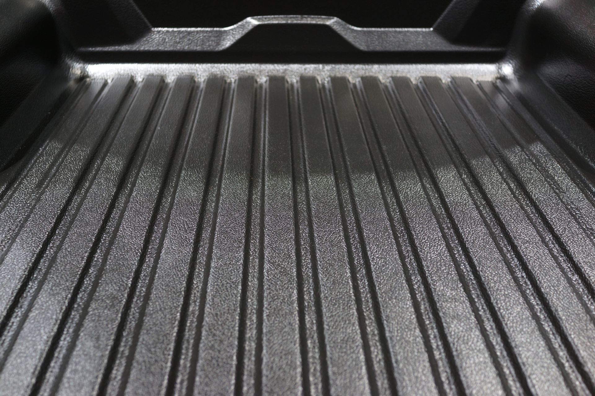 Black textured truck bed with vertical grooves.