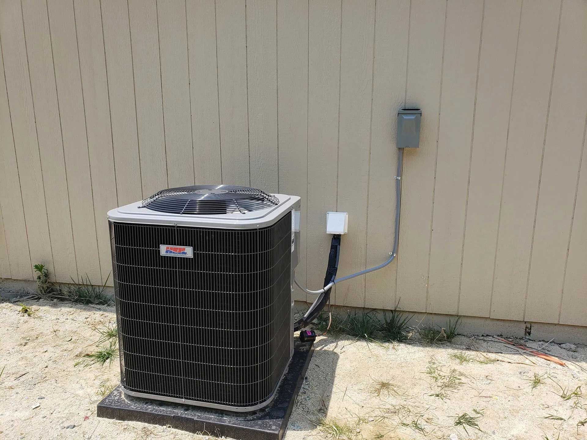 AC unit against a wall with electrical box.