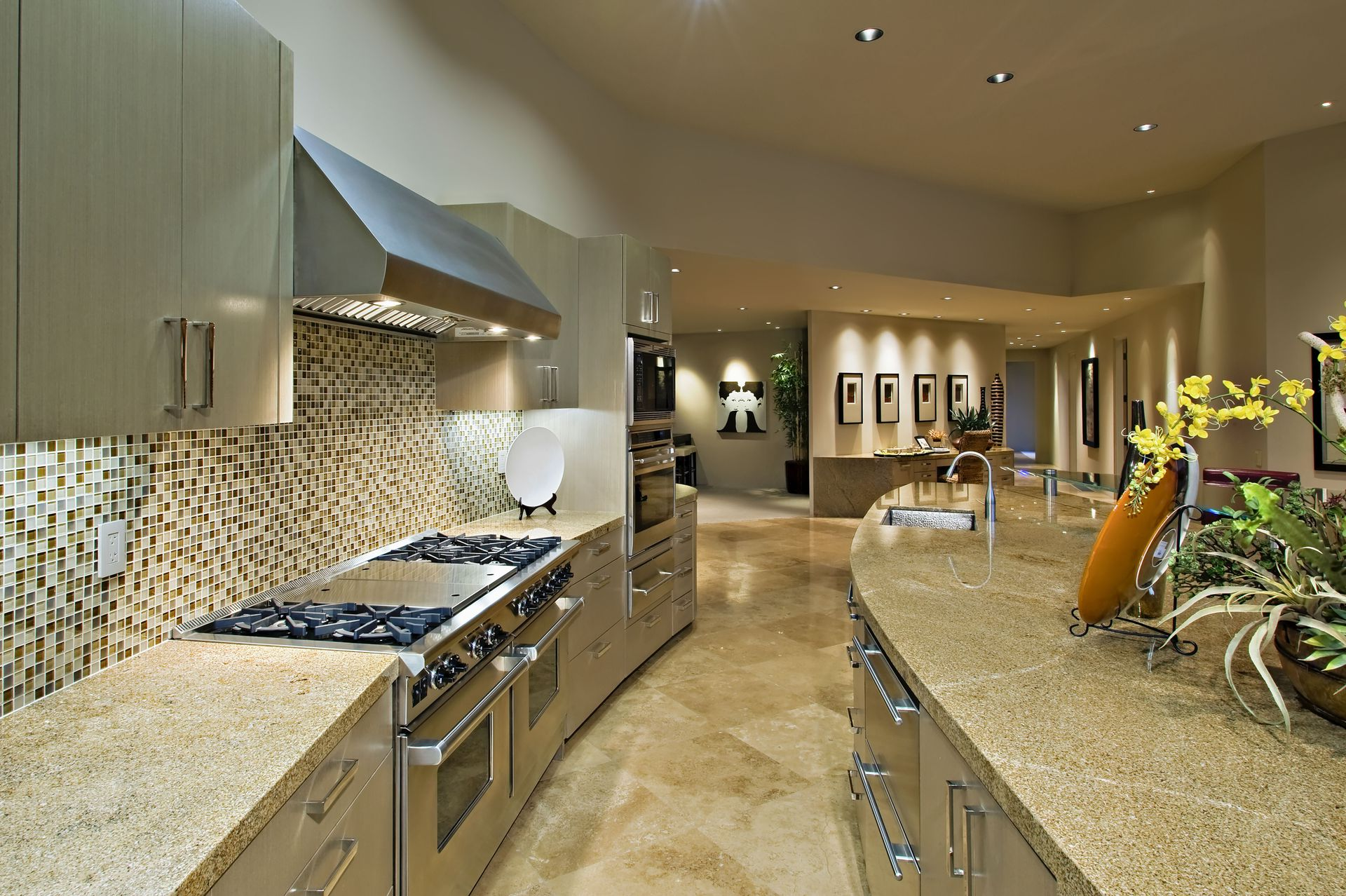 Modern kitchen with curved granite countertops, stainless steel appliances, and mosaic backsplash.