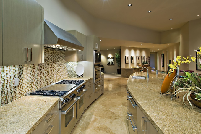 Modern kitchen with curved granite countertops, stainless steel appliances, and mosaic backsplash.