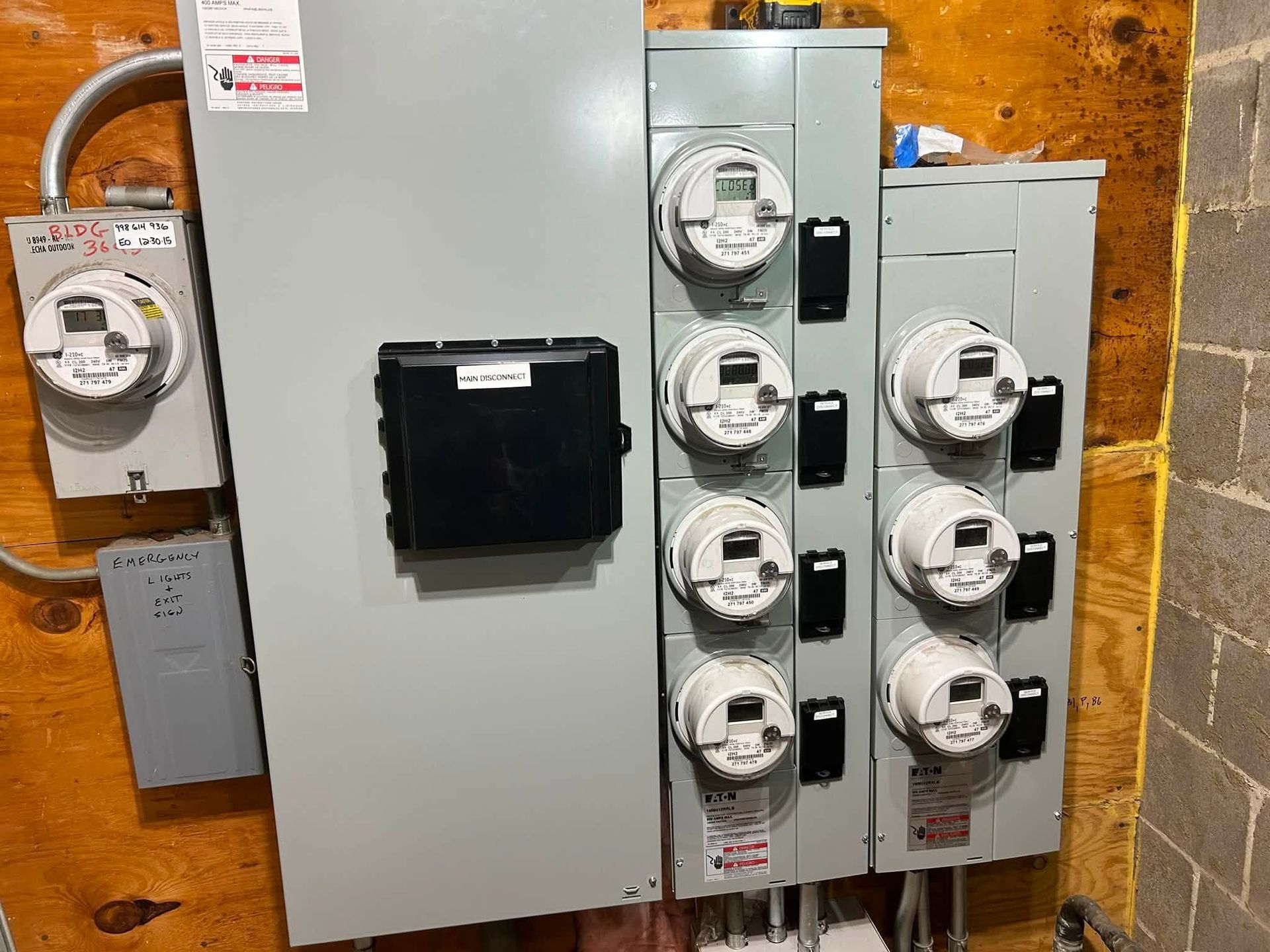 Electrical meter panel with multiple utility meters on a wall in a basement-like utility room