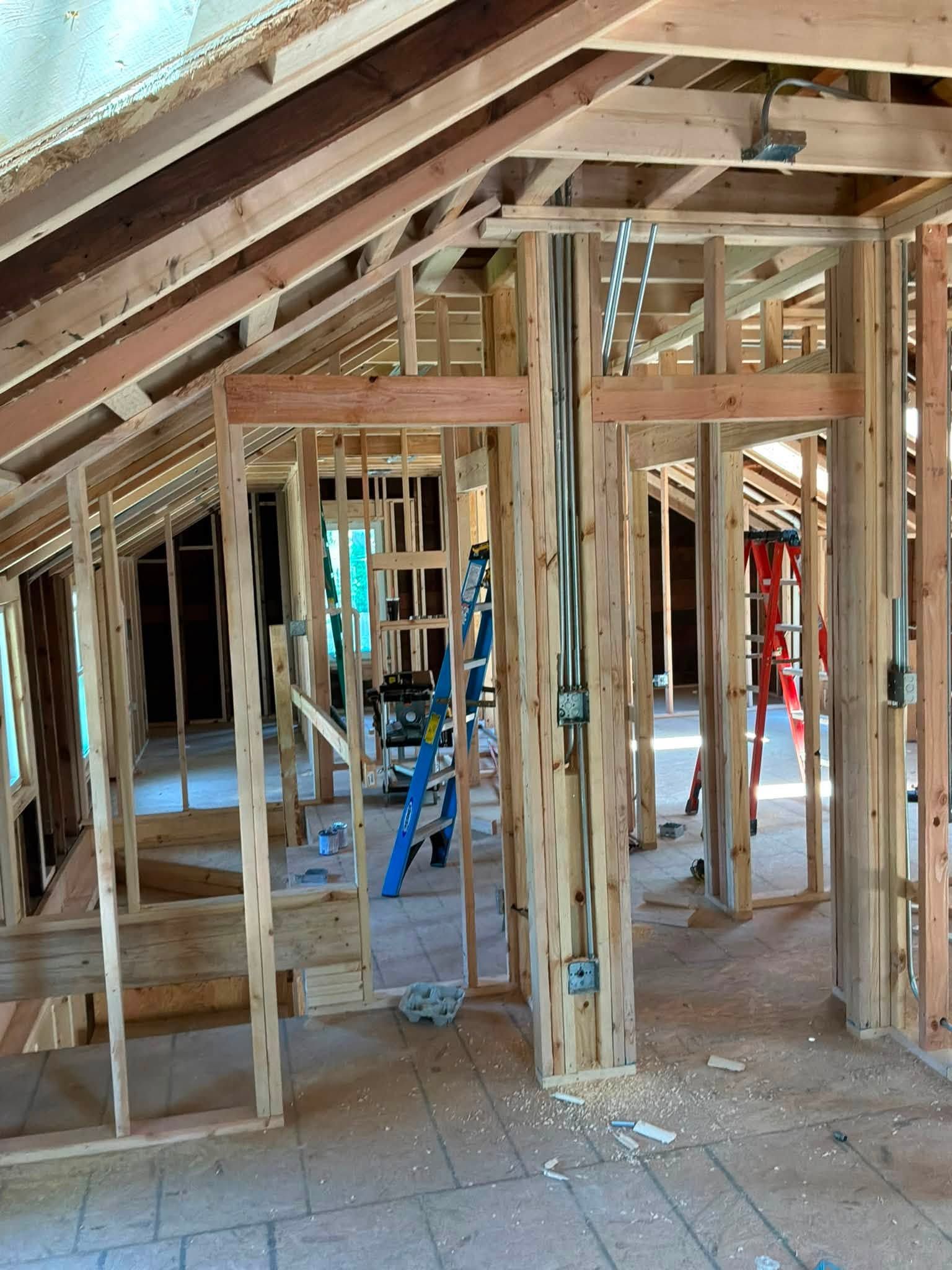 Interior of a house under construction with exposed wooden framing and slanted roof rafters