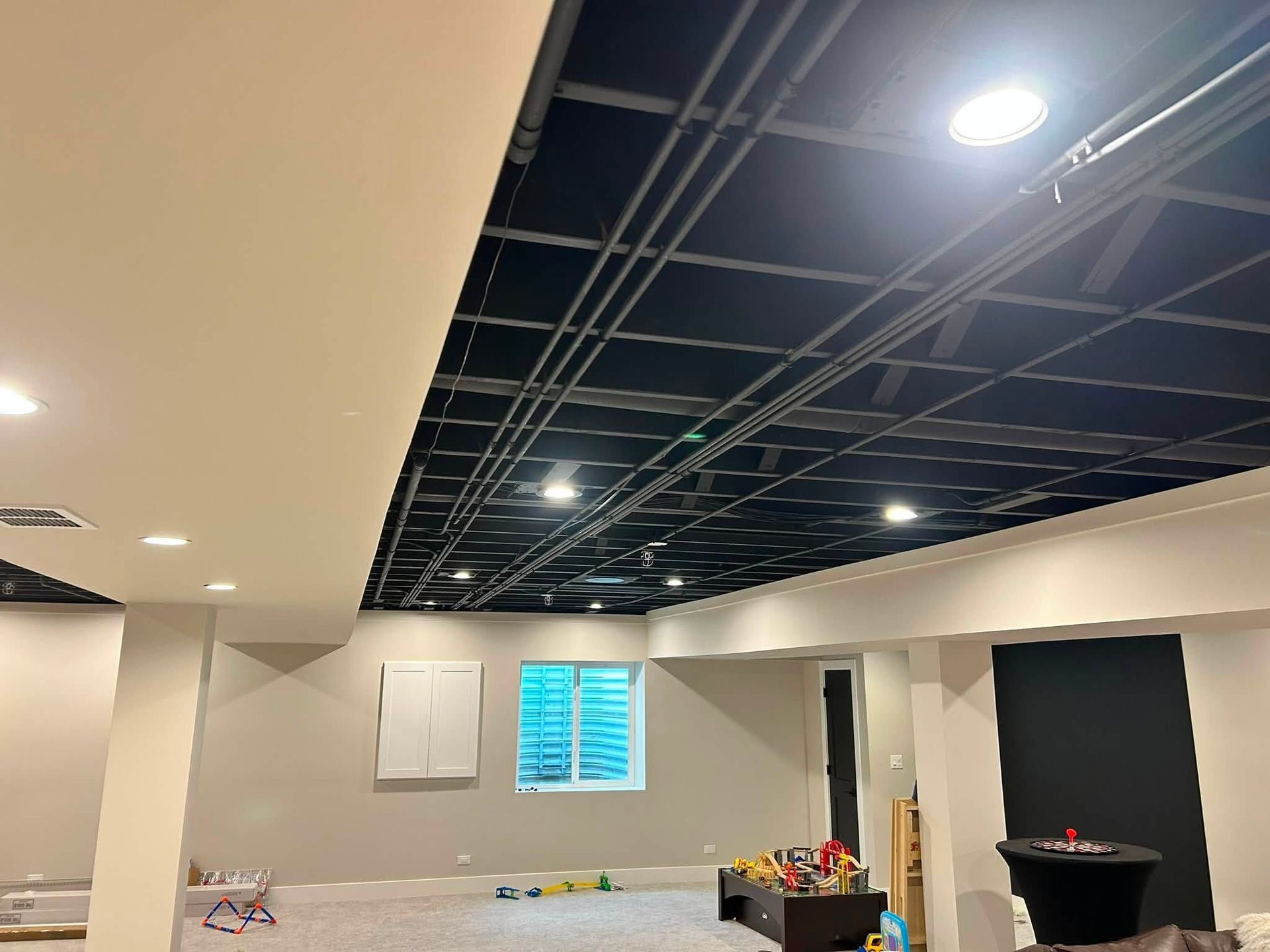 Partially finished room with recessed lights, exposed ceiling grid, and blue window blinds