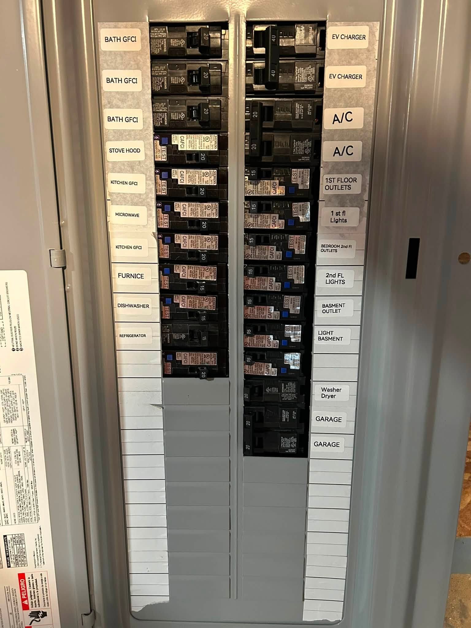 Open electrical breaker panel with labeled circuit switches in a wall niche.