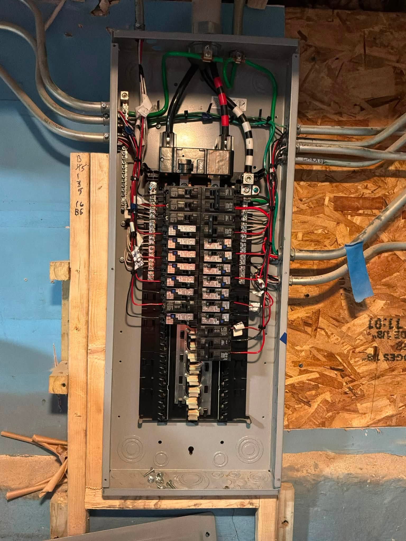 Open electrical breaker panel with exposed wiring in a basement wall cavity