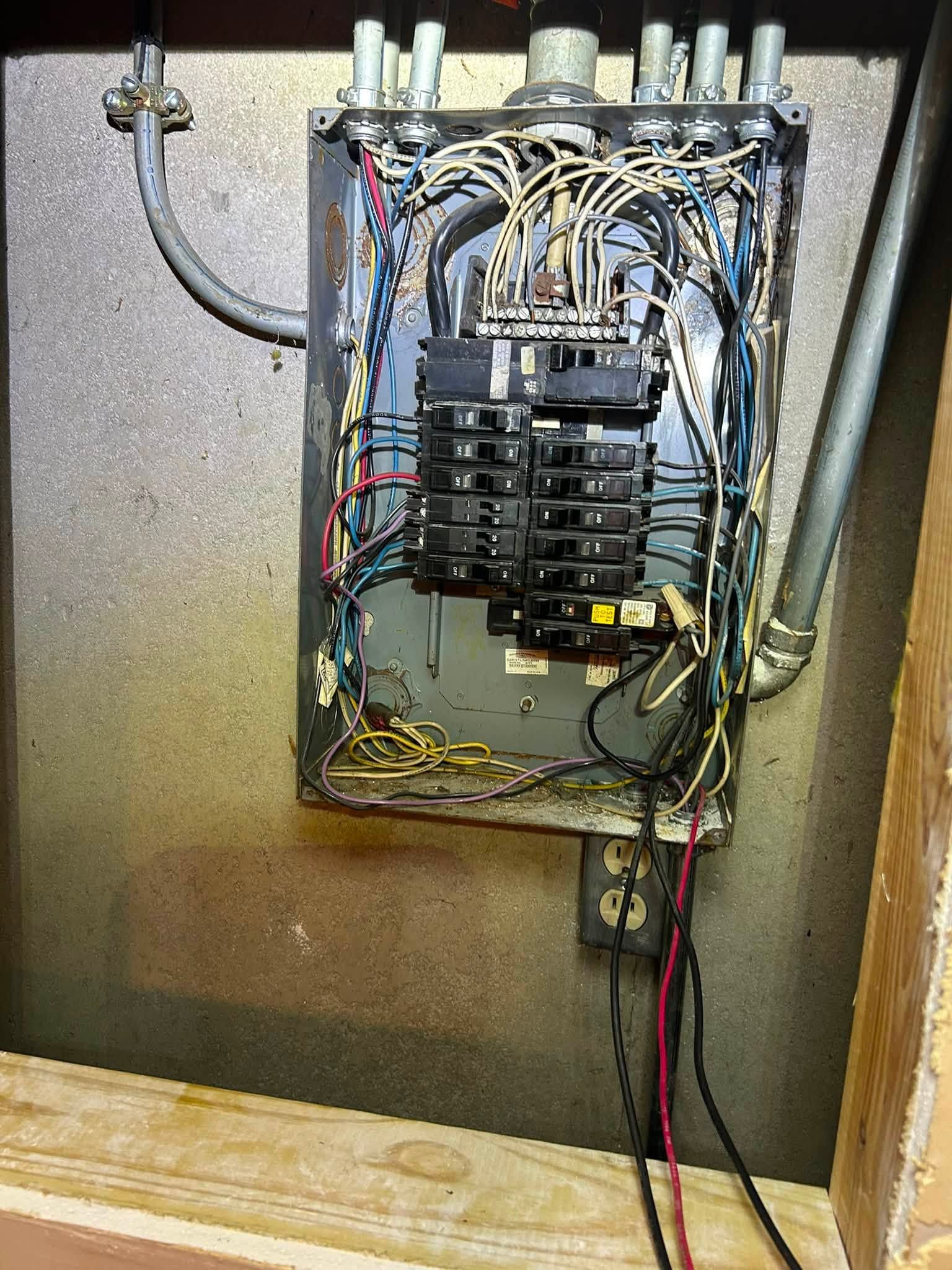 Open electrical breaker panel with tangled wires in a utility cabinet