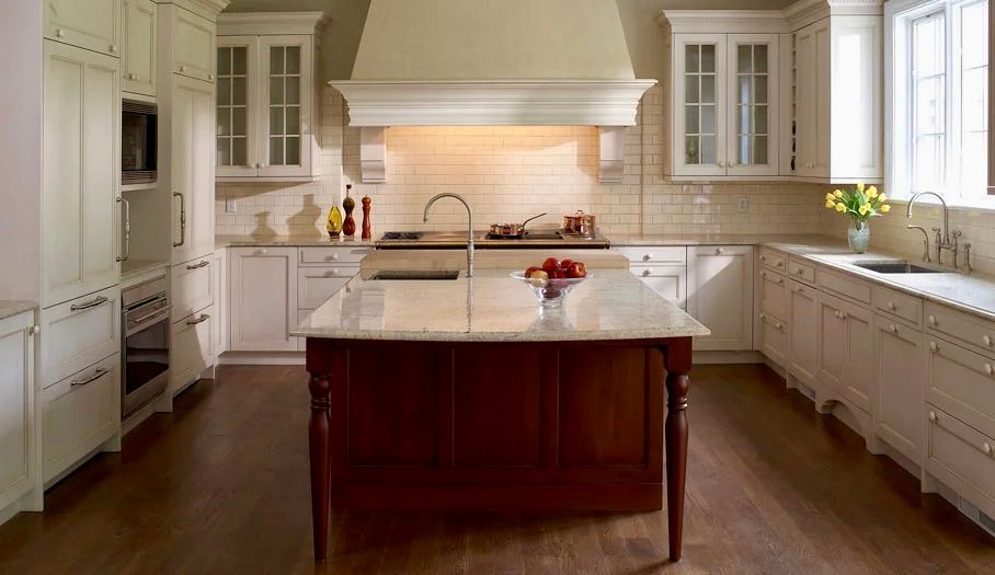 Elegant white kitchen with a dark wood island, a range, and marble countertops.