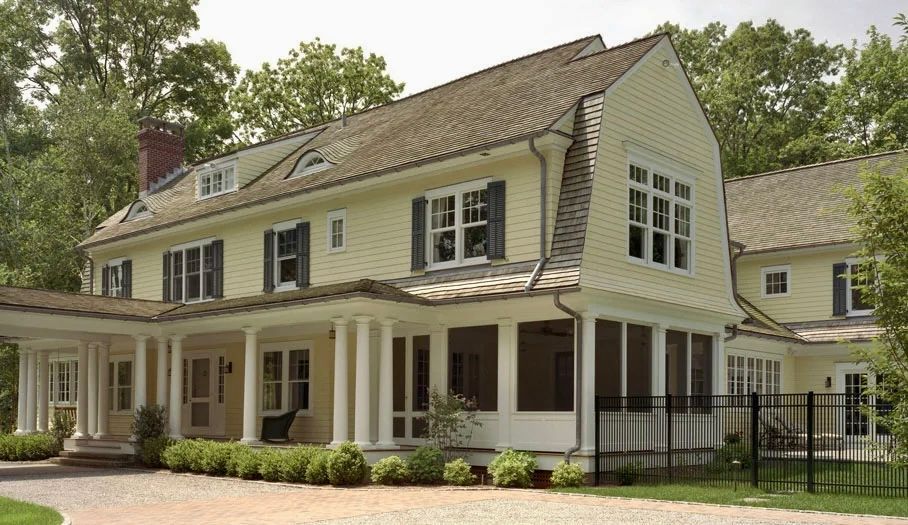 Yellow two-story house with white columns, shutters, and porch. Brick driveway.