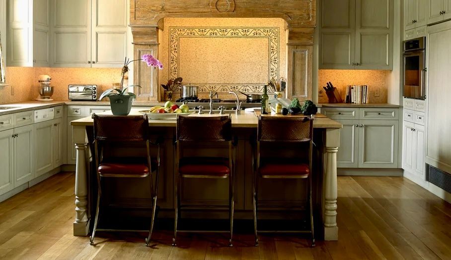 Kitchen with light blue cabinets, wooden island with three stools, and built-in appliances.