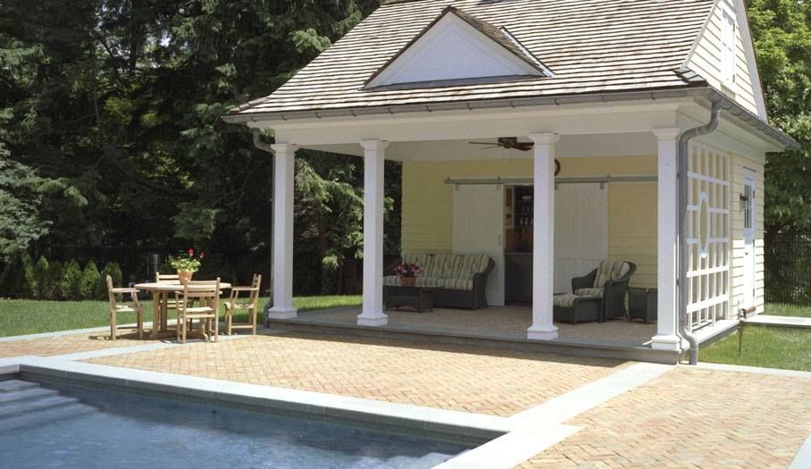 Poolside cabana with columns, patio furniture, and pool.