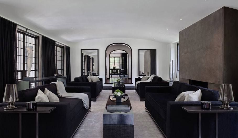 Spacious living room with black couches, a grey rug, and mirrors, with a neutral color palette.
