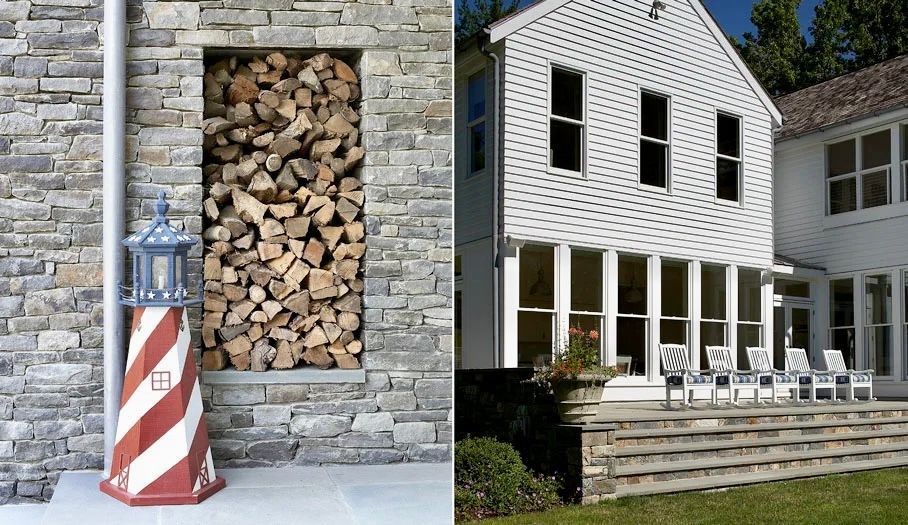Lighthouse statue and firewood storage nook built into a stone wall next to a white house with a patio.