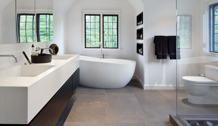 Modern white bathroom with freestanding tub, double sink, and gray tile floor.