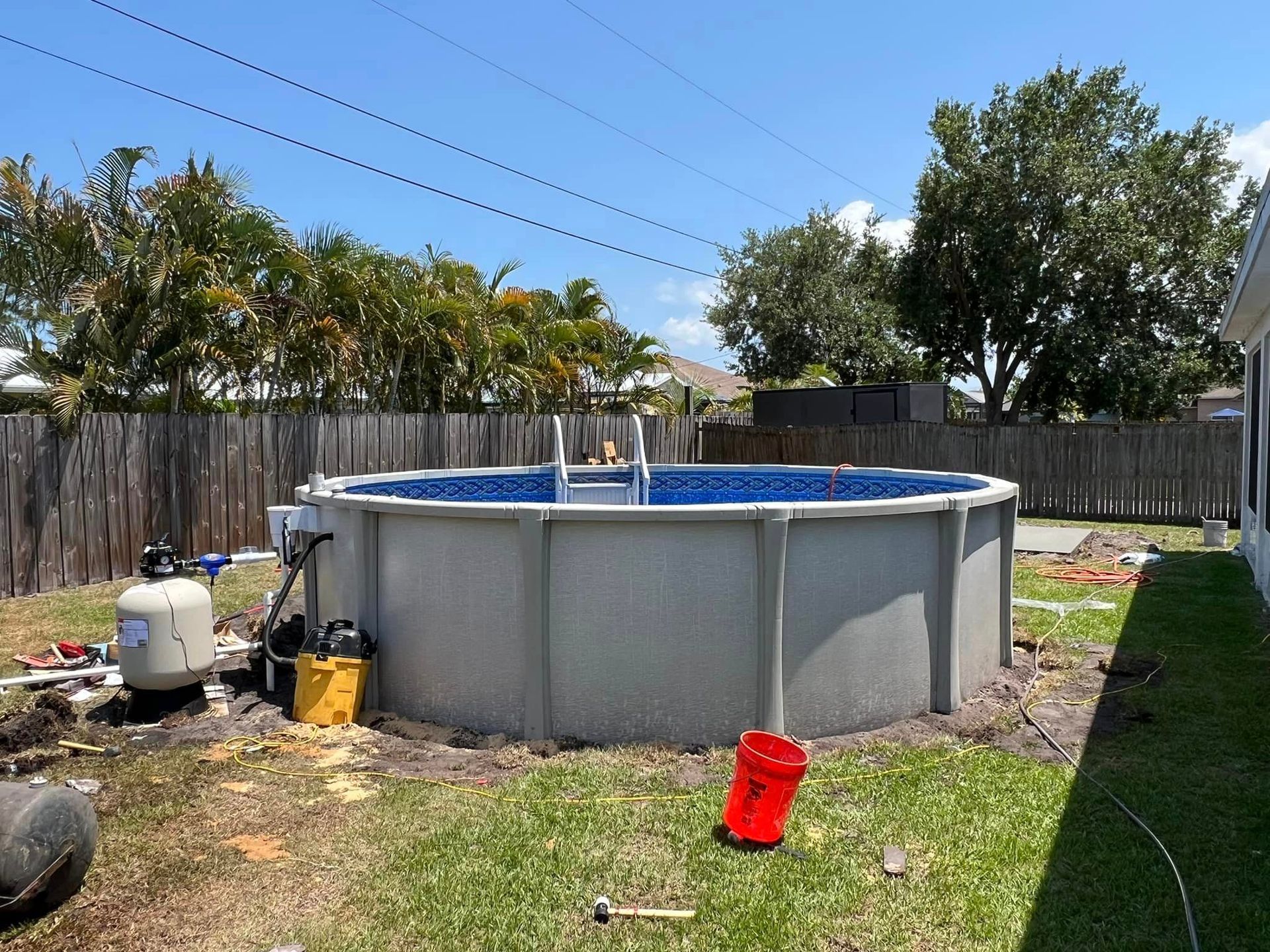 A large swimming pool is being built in the backyard of a house.