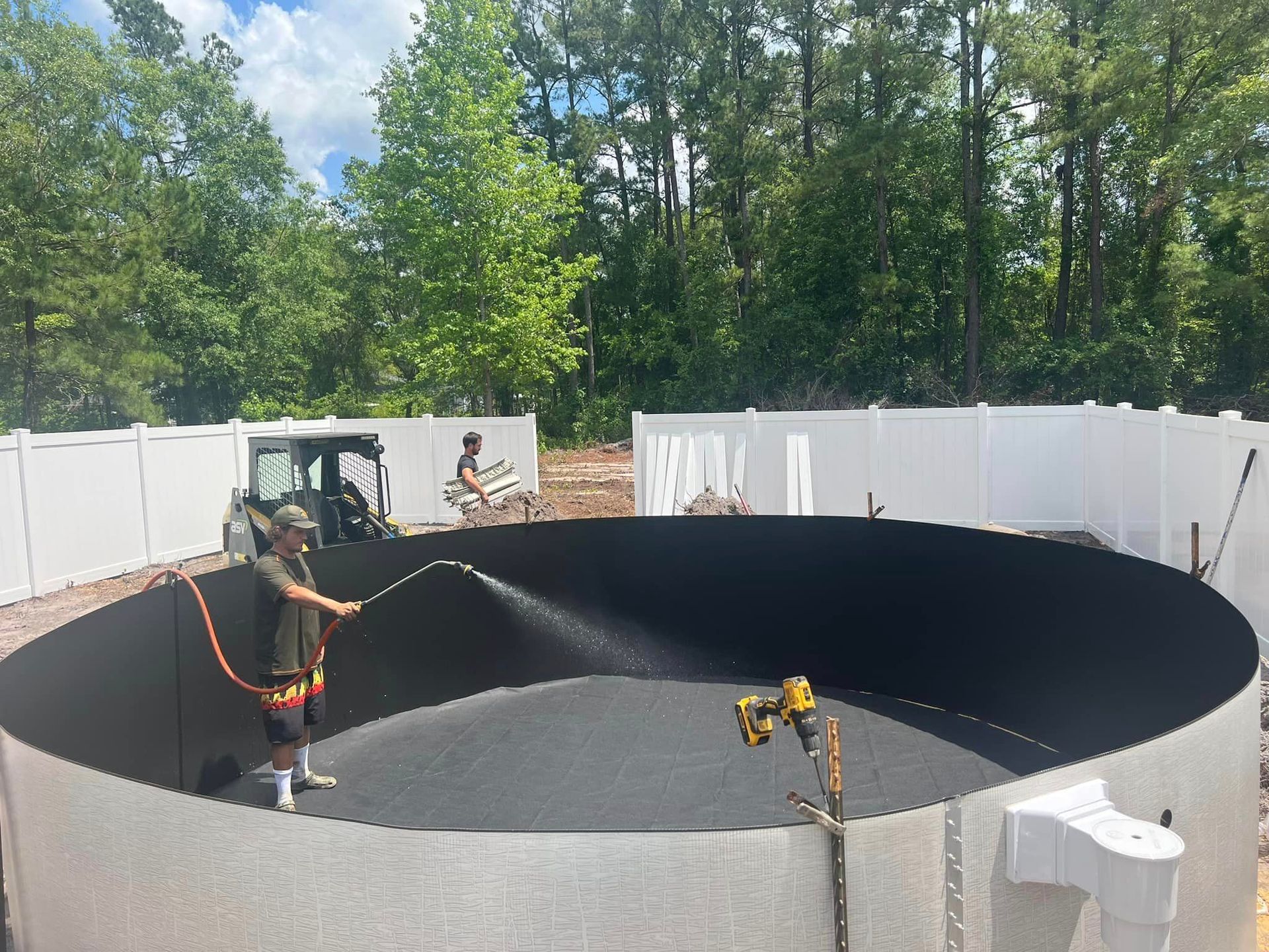 A man is spraying a pool with a hose.