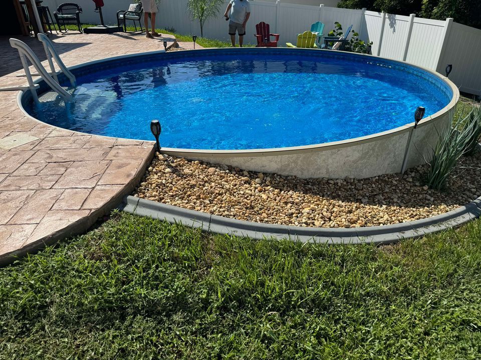 A large swimming pool is sitting in the middle of a lush green yard.