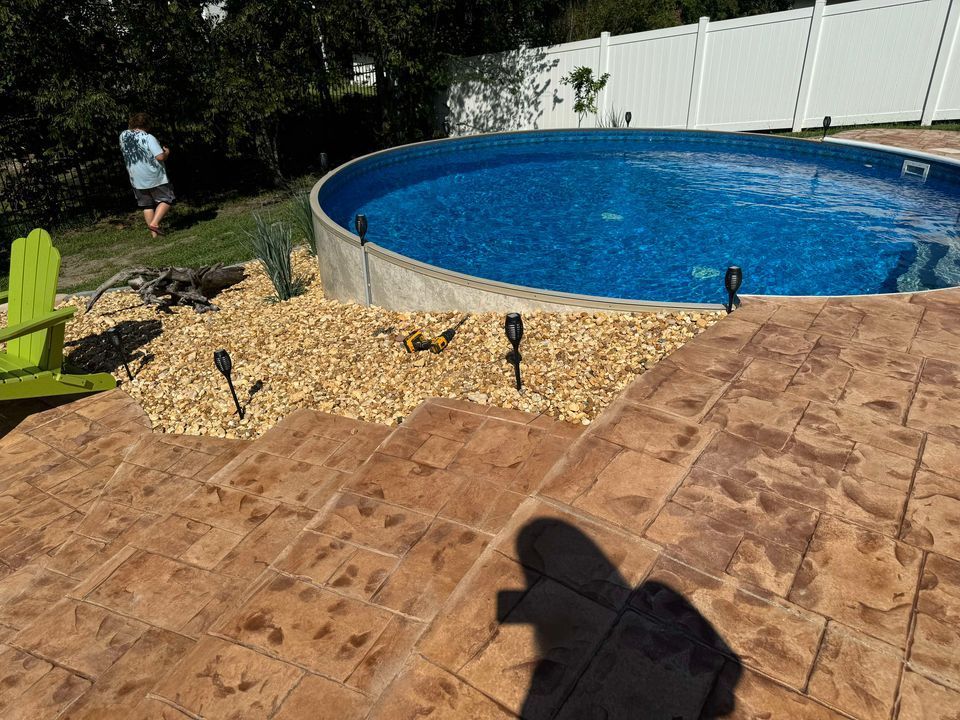 A man is standing next to a swimming pool in a backyard.