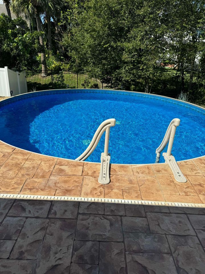 A large swimming pool with stairs leading to it is surrounded by trees.
