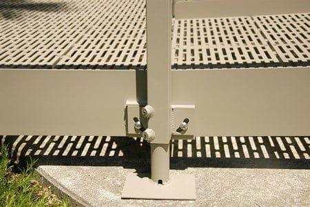 A close up of a metal fence with a shadow on the ground