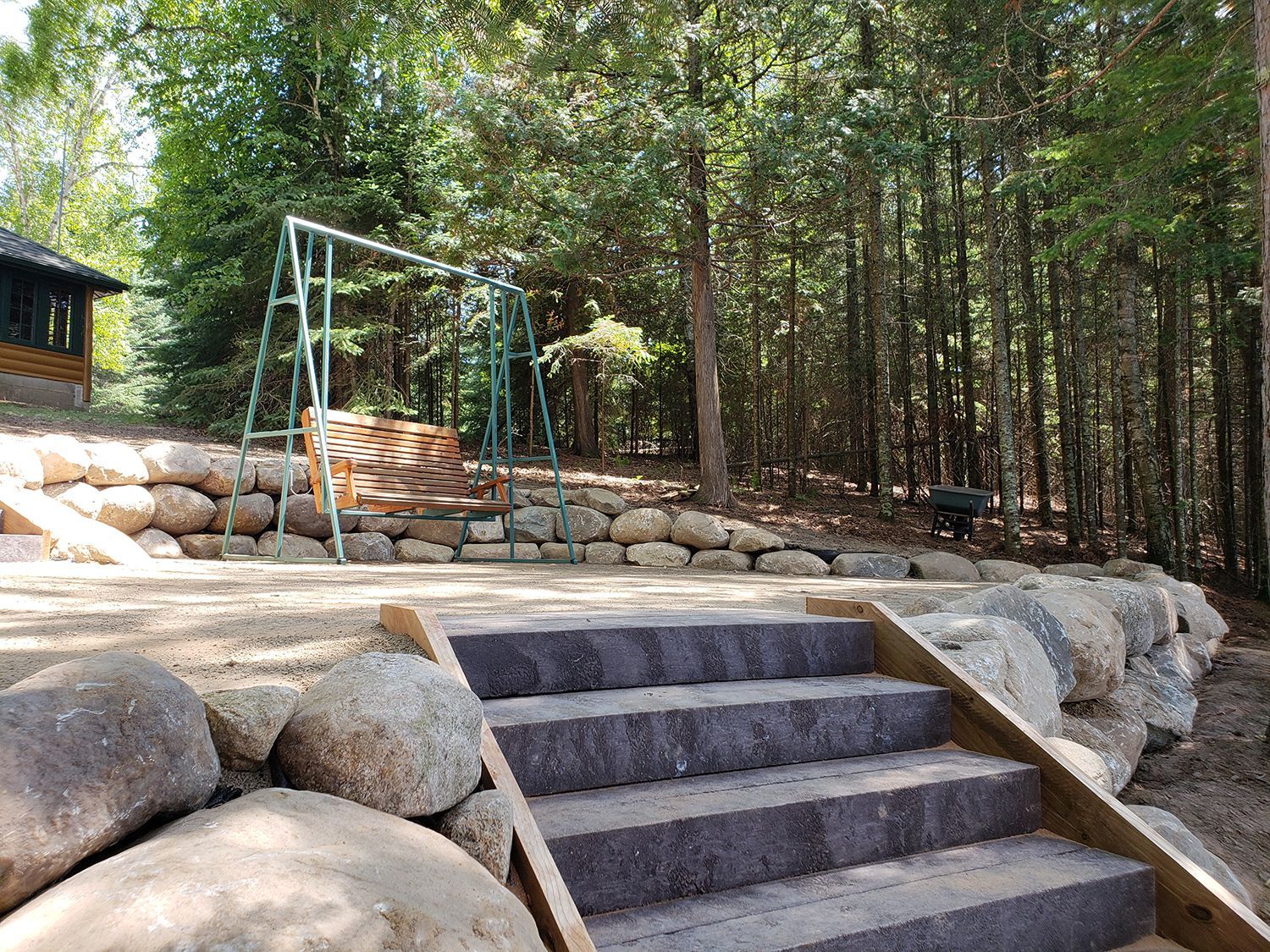 A set of stairs leading up to a rock wall in the woods.