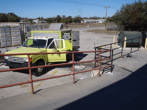 A yellow truck is parked next to a red fence
