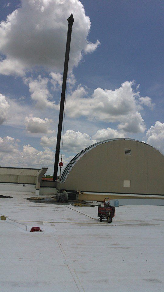 A large crane is sitting on top of a white roof.