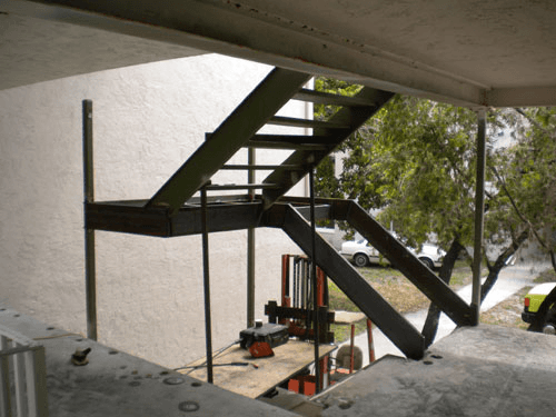 A yellow truck is parked in front of a staircase under construction