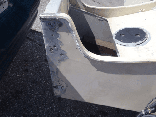 A boat is sitting on the ground next to a car