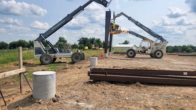 A couple of construction vehicles are sitting on top of a dirt field.