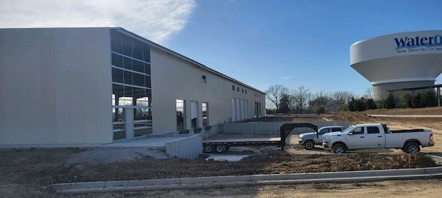 A white truck is parked in front of a building under construction.