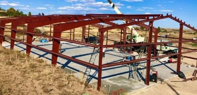 A large metal structure is being built in the middle of a field.
