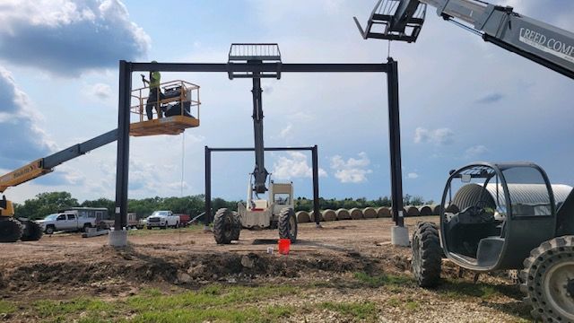 A group of construction workers are working on a building in a field.
