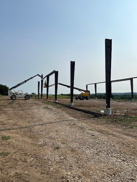 A fence is being built in a dirt field.