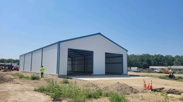 A man in a yellow vest is standing in front of a large white building.