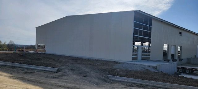 A large white building is being built in the middle of a dirt field.