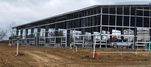 A large building is being built in a dirt field.